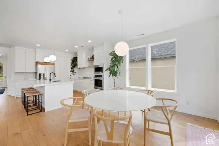 Modern kitchen with white cabinetry, stainless steel appliances, and a central island with a sink