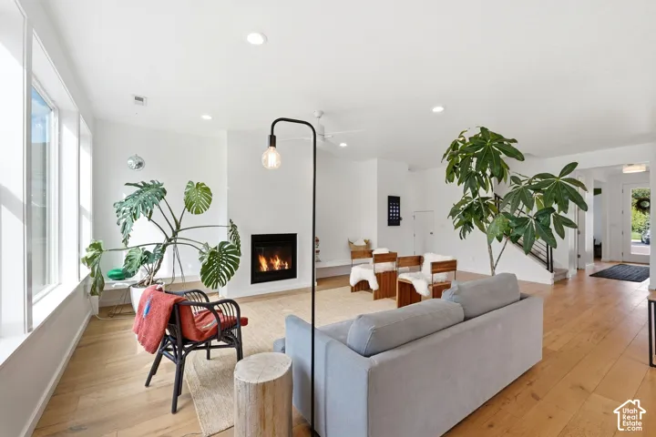 Spacious living area featuring light wood-finish flooring, a contemporary fireplace, and recessed lighting