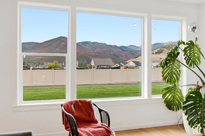 Expansive multi-pane window with mountain scenery, a manicured lawn, and wood-finish flooring