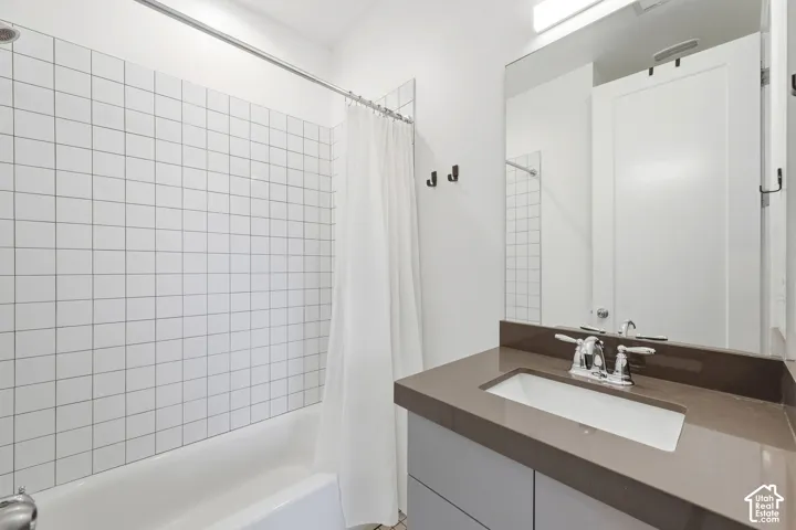 Subway tile shower surround, integrated bathtub, vanity with an undermount sink, and a large wall-mounted mirror