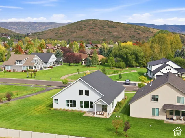 Expansive green spaces surround contemporary residences with mountain terrain in the background