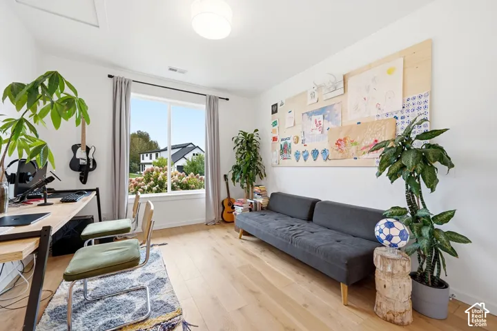 Hardwood-finish flooring, white walls, large window with white trim, recessed light fixture, built-in wall panel