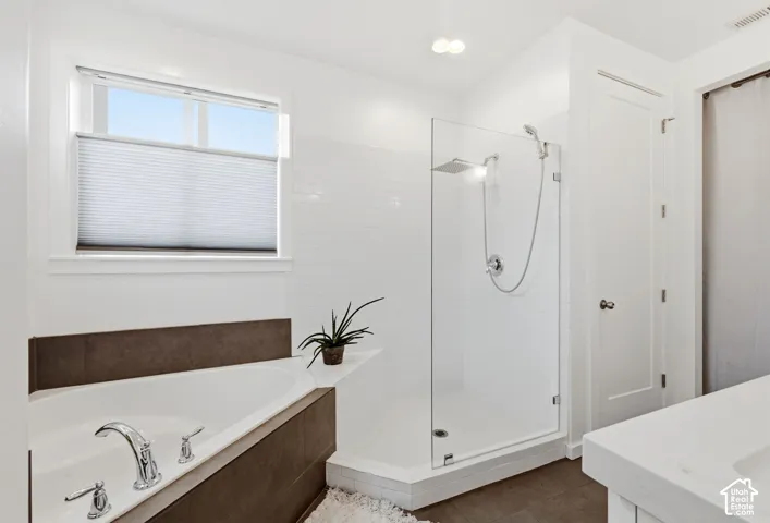 Freestanding soaking tub with chrome fixtures, glass-enclosed shower with a rainfall showerhead, white subway tile surround, and neutral-toned flooring