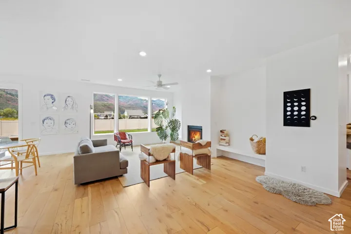 Bright open-concept living area featuring wood-finish flooring, a contemporary fireplace, and recessed lighting
