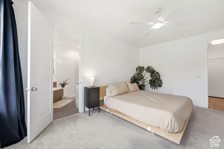 White walls, grey carpet flooring, and a ceiling fan with integrated lighting