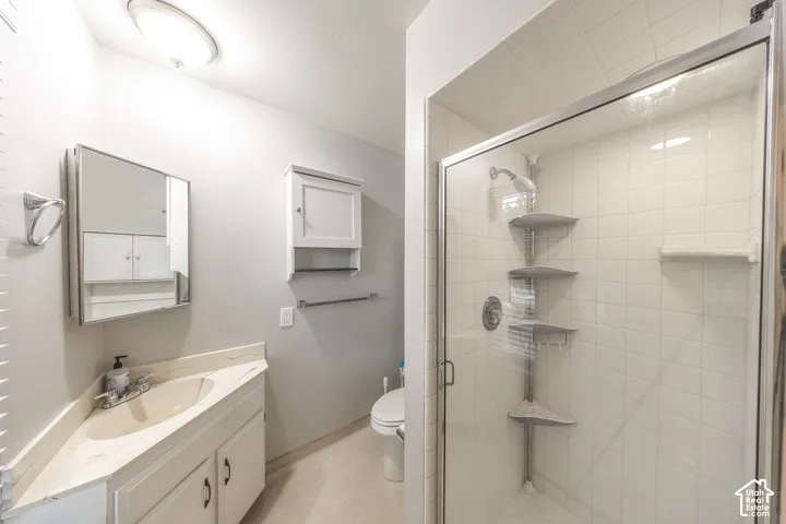 Corner vanity with integrated sink, white cabinetry, and wall-mounted mirror