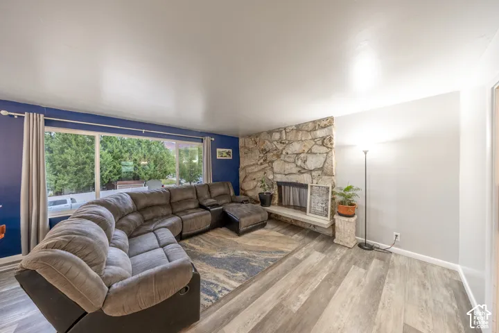 Stone-faced fireplace with hearth, wood-finish flooring, and large window