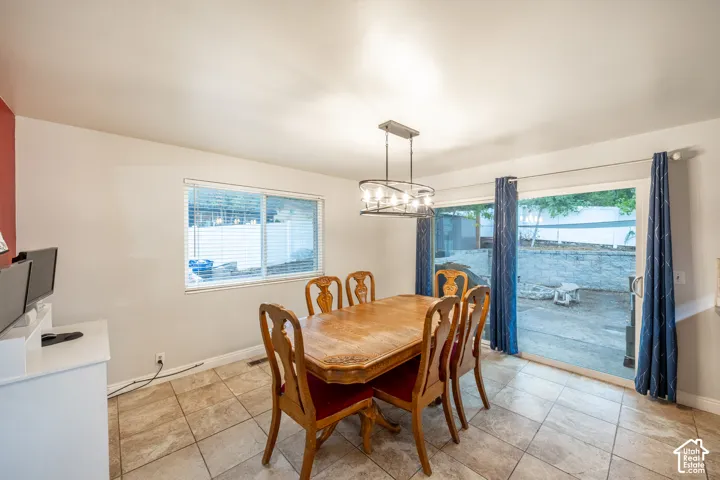 Tiled flooring, modern chandelier, double-pane window, sliding glass door, and a retaining wall in the outdoor area