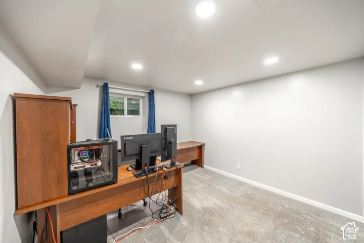 Recessed ceiling lighting, carpeted flooring, light grey painted walls, and a window with blue drapes