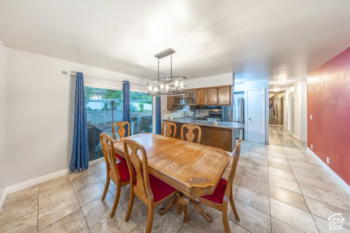 Dining area with ceramic tile flooring, a glass sliding door, and an open-concept kitchen featuring wood cabinetry and stainless steel appliances