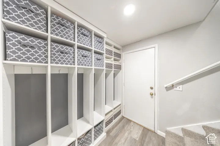 Built-in storage cubbies with integrated hooks, wood-finish flooring, and a white interior door