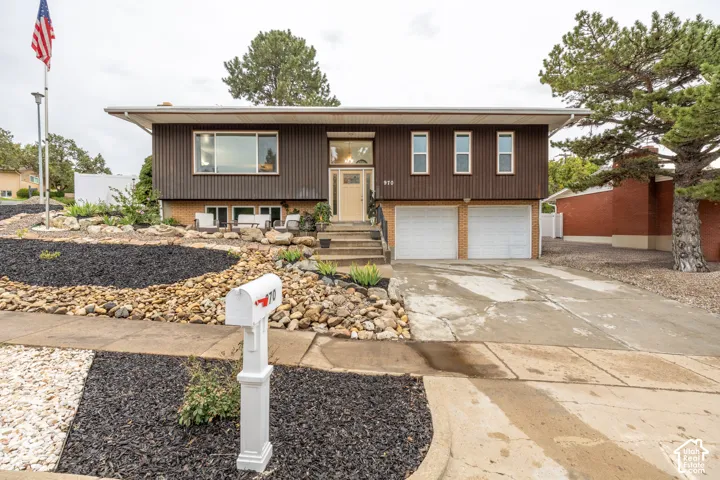Split-level residence featuring a two-car garage, concrete driveway, and a front entry staircase