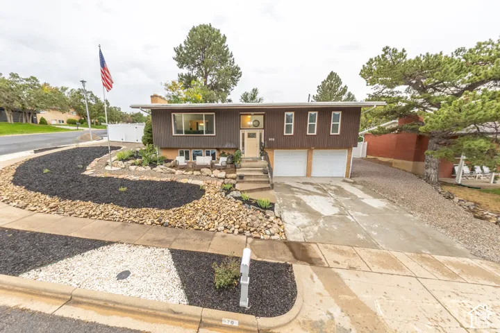 Mid-century modern exterior featuring a two-car garage, concrete driveway, and front landscaping with decorative rock and mulch