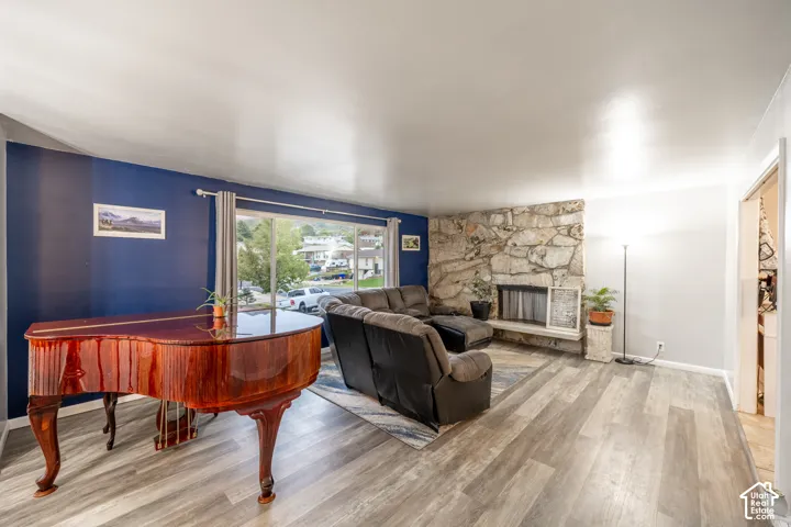 Spacious living area featuring wood-finish flooring, a stone fireplace, and large picture windows