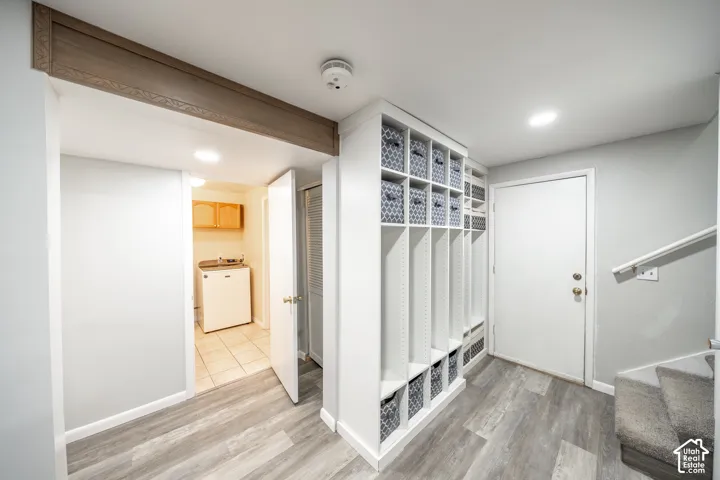 Wood-finish flooring, built-in storage shelving, overhead lighting, and a utility sink with wood cabinetry