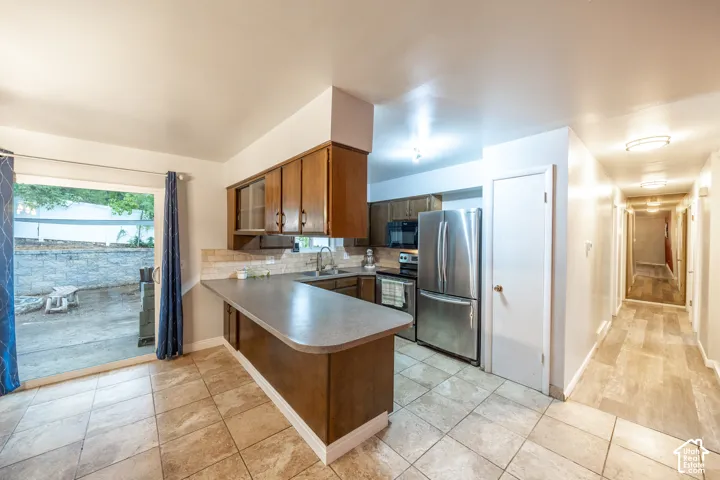 Kitchen featuring wood-finish cabinetry, stainless steel appliances, and a tile backsplash
