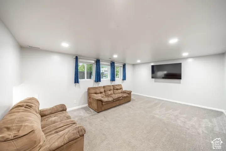 Spacious room featuring light gray carpet, white walls, and recessed lighting