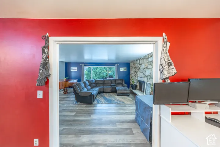 Living area featuring wood-finish flooring, a stone accent wall with a fireplace, and a large window