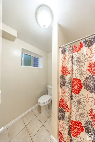 Recessed window, white toilet, tile flooring, ceiling-mounted light fixture