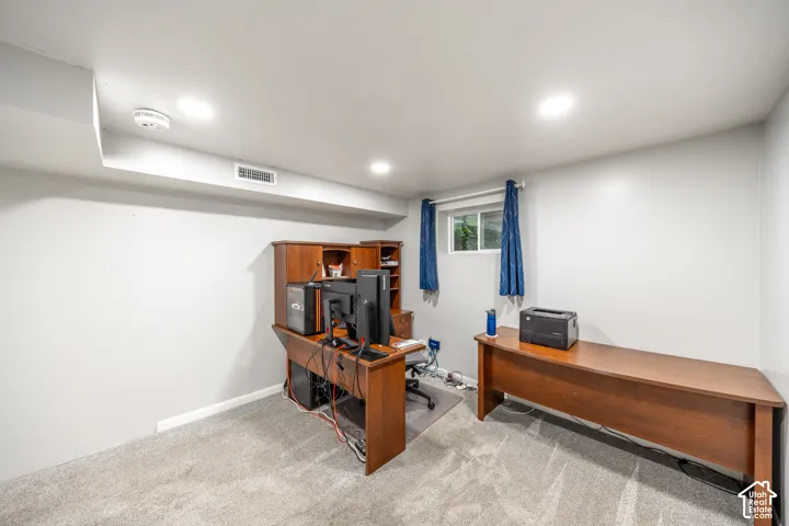 Recessed lighting, light gray carpeting, and a window with blue drapes