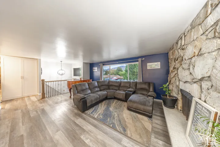 Living area featuring wood-finish flooring, a stone-accented fireplace, built-in cabinetry, and a railing with dark balusters