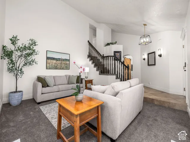 Vaulted ceilings, carpeted flooring, staircase with wood banister and balusters, and recessed entryway with floor tiling