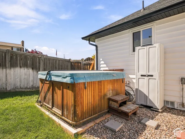 Private backyard area featuring a hot tub with wood-finish siding, a section of gravel hardscaping