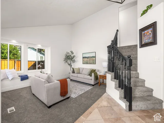 Vaulted ceiling, window seating, carpeted flooring, tile flooring, and a staircase with dark wood balusters
