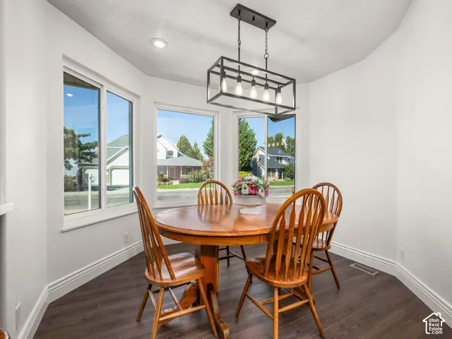 Bay window with multiple panes, dark wood-finish flooring, recessed ceiling lighting, and a linear black-frame chandelier