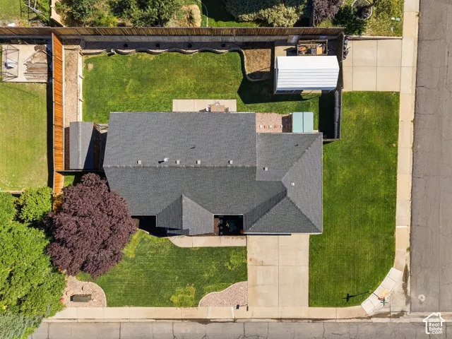 Gable roofline, expansive lawn, mature landscaping, paved driveway, and perimeter fencing