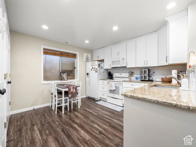 White cabinetry with brushed nickel hardware, granite-style countertops, wood-finish flooring, and recessed lighting