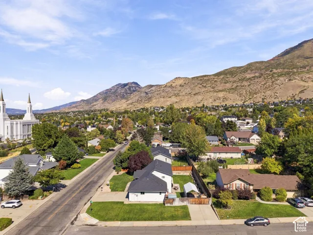 Residential street with paved road, manicured lawns, and mature trees
