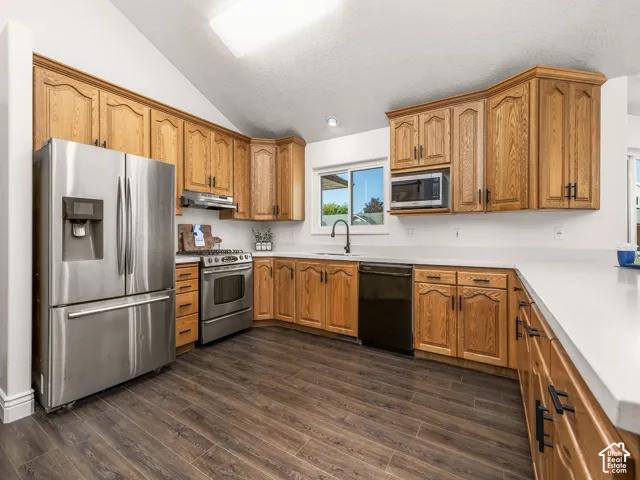 Kitchen featuring wood-finish cabinetry, stainless steel refrigerator, stainless steel range, built-in microwave, and wood-finish flooring