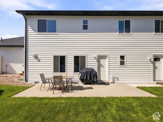 Expansive concrete patio with multiple access points to the property, surrounded by a lush lawn and decorative rock landscaping