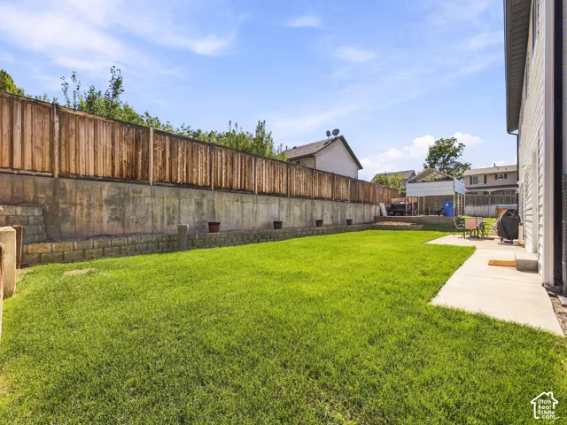 Expansive green lawn, concrete patio, wood privacy fence, concrete retaining wall, and block retaining wall