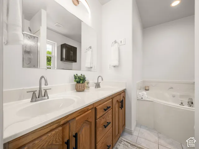 Dual vanity with white countertop and brushed nickel faucets, wood-finish cabinetry, built-in corner tub, and a glass-enclosed shower