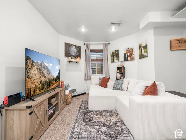 Recessed lighting illuminates this space featuring light-colored walls, a window with blinds, and a built-in entertainment console with barn-door style accents