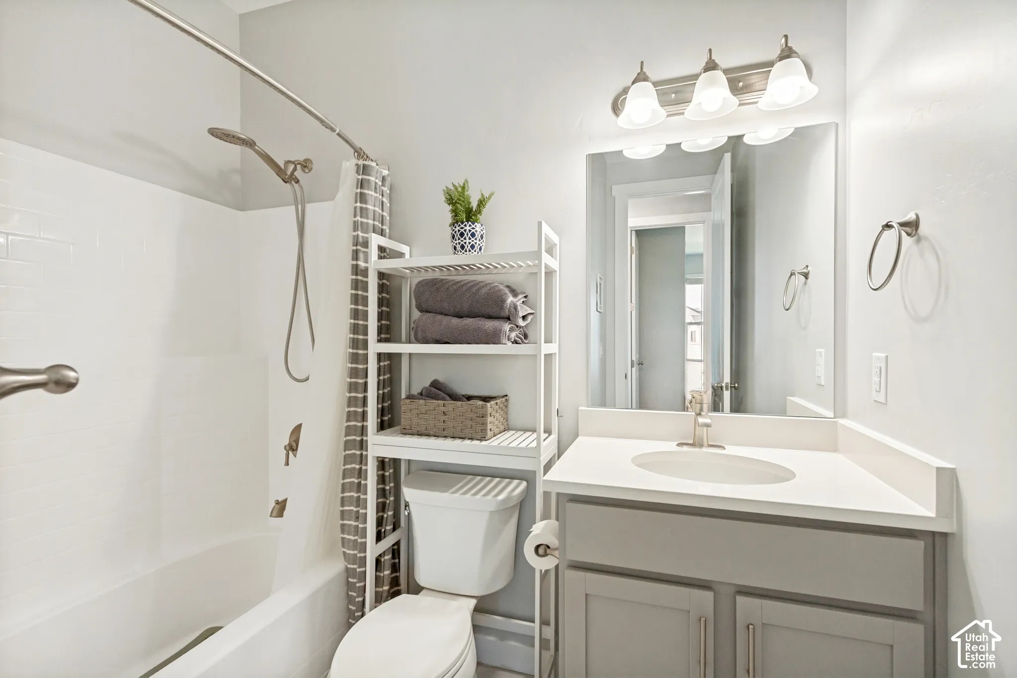 Vanity with integrated sink and countertop, brushed nickel faucet, large wall mirror, and three-light fixture