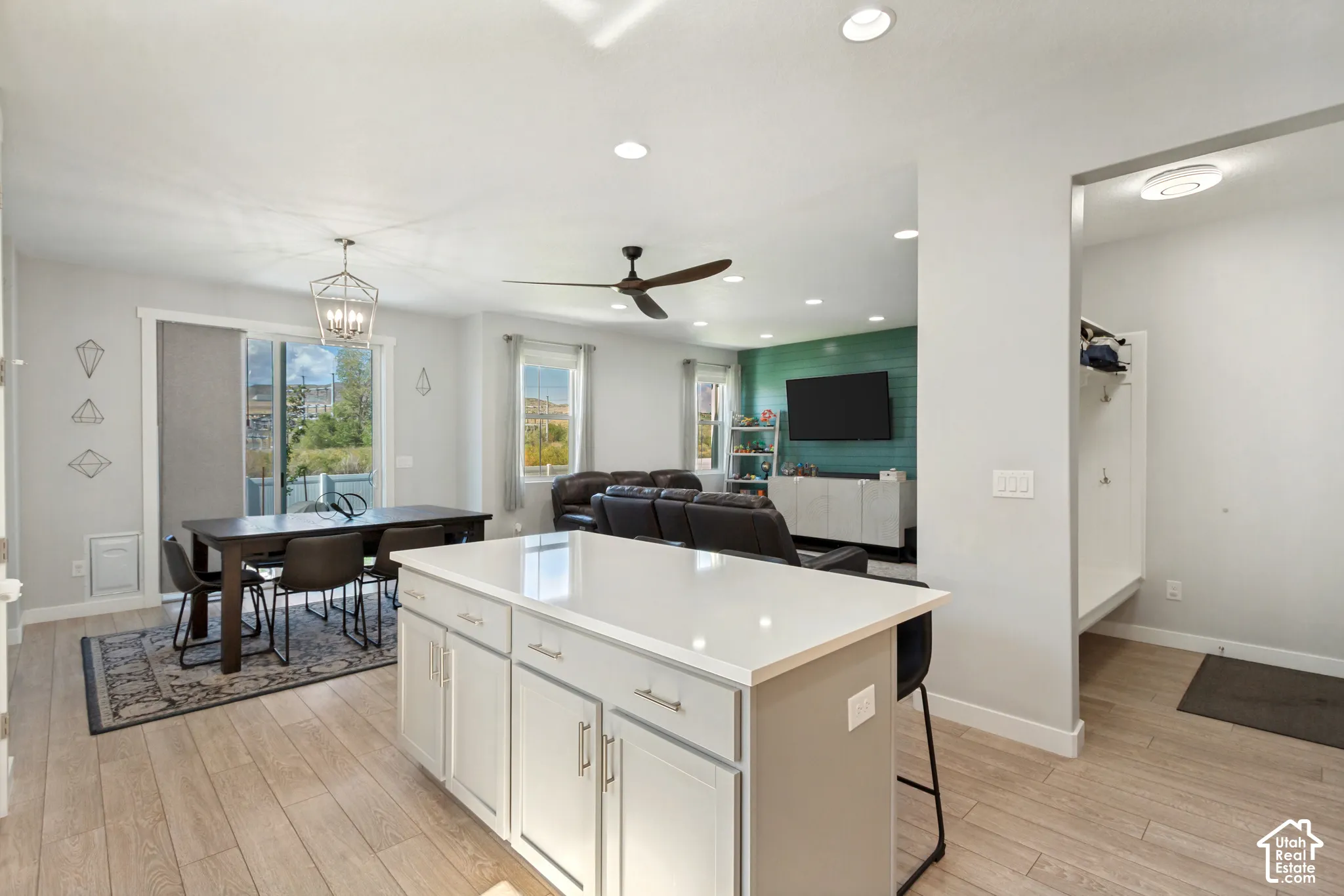 LVP flooring throughout, kitchen island with solid surface countertop, recessed lighting, ceiling fan, and sliding glass door