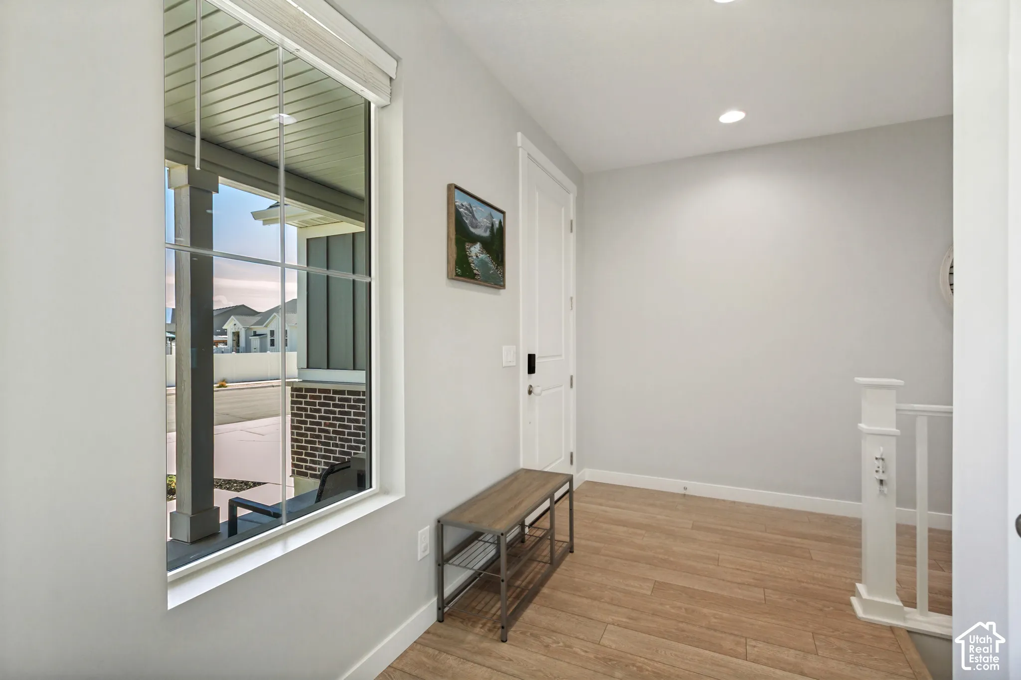 Expansive window with grid panes, recessed ceiling lighting, LVP flooring, and a white paneled interior door with dark hardware