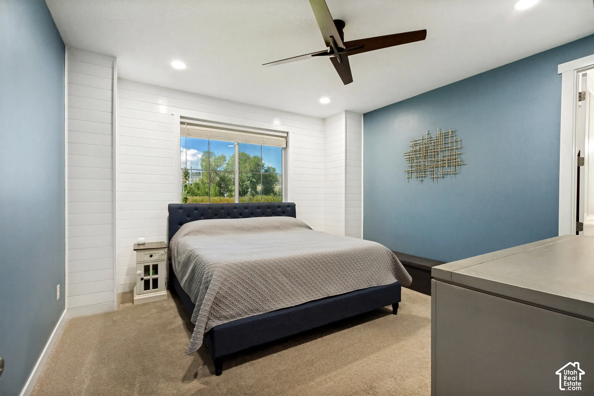 Recessed lighting, ceiling fan, shiplap accent wall, window with roller shade, carpet flooring