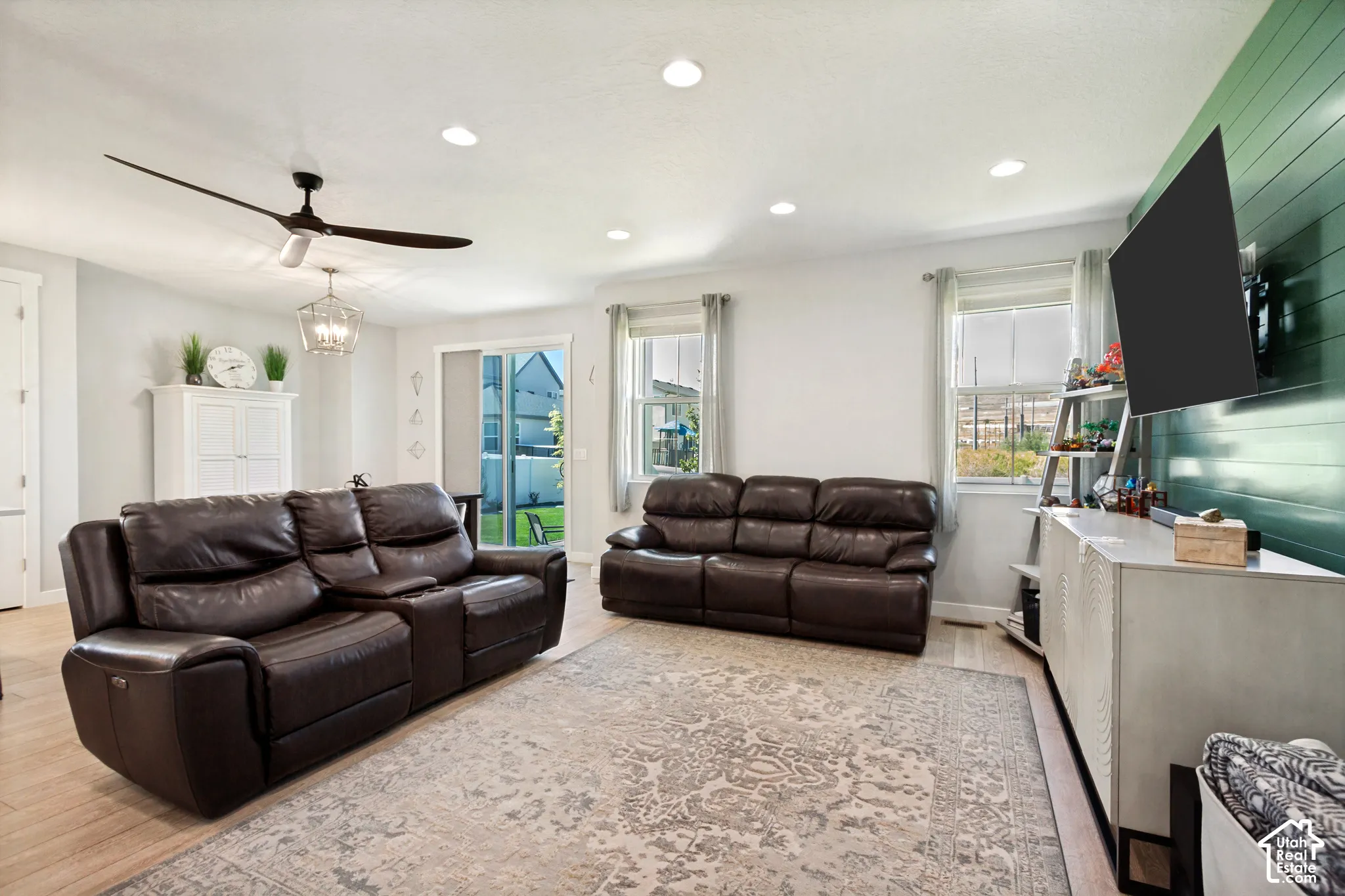 Recessed lighting, LVP flooring, ceiling fan, sliding glass door, and accent wall with horizontal paneling