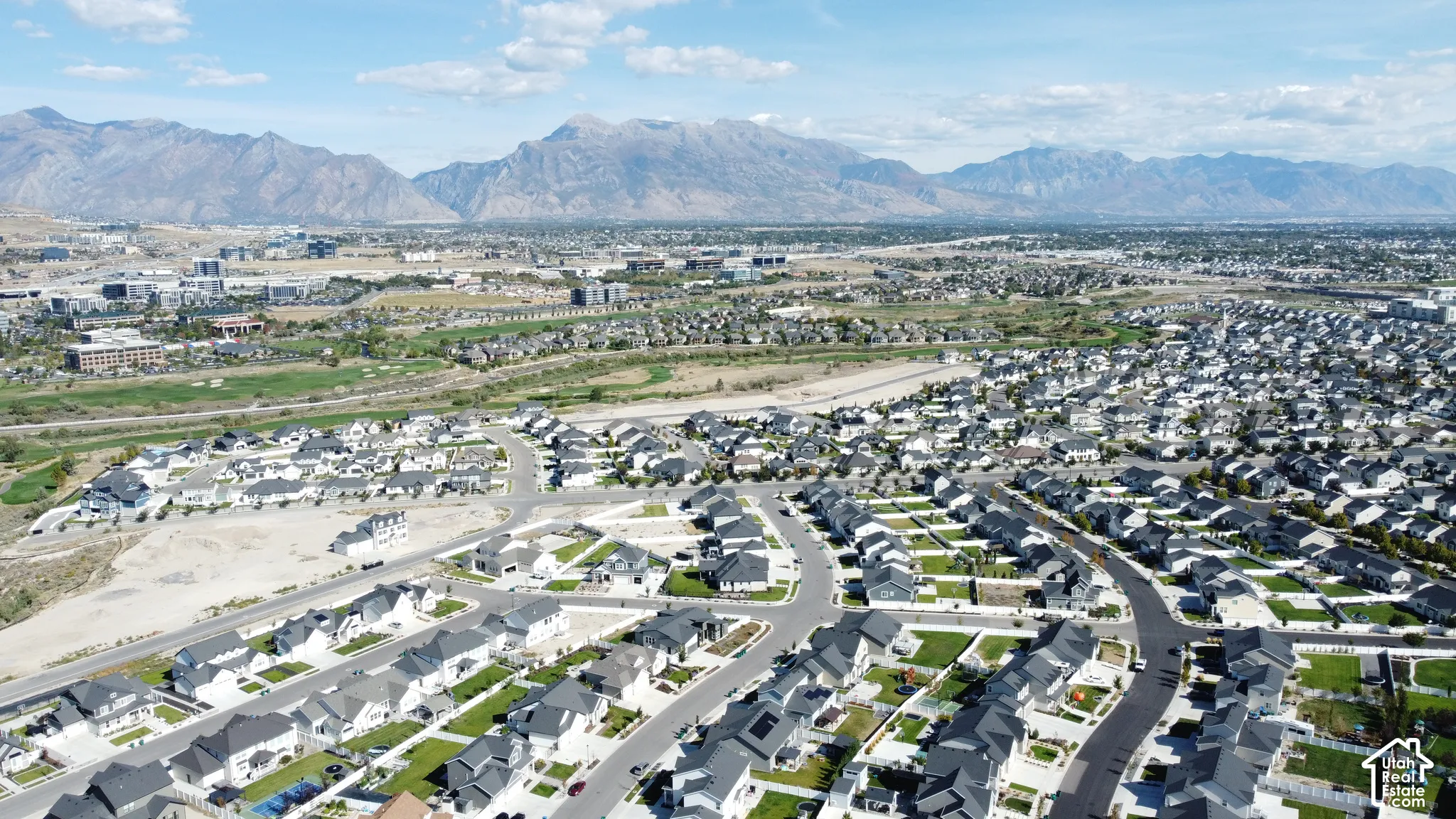 Extensive residential development with a mountain backdrop, featuring a mix of established homes and new construction