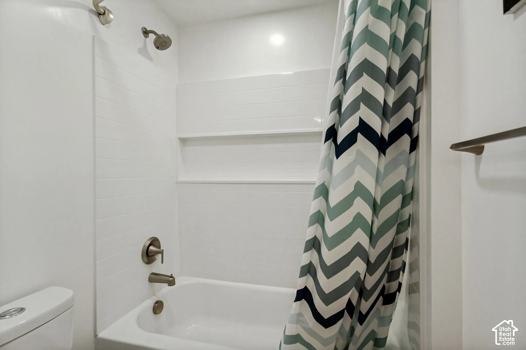 White tiled shower with brushed nickel fixtures and integrated shelving