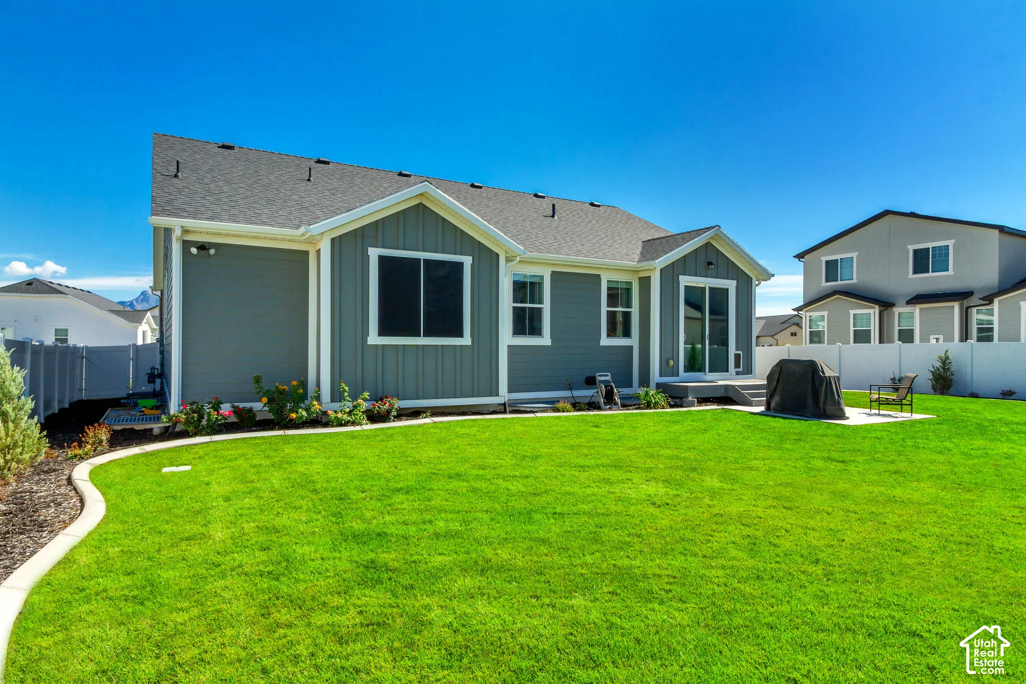 Expansive backyard featuring a manicured lawn, established landscaping, and a patio with a concrete pad