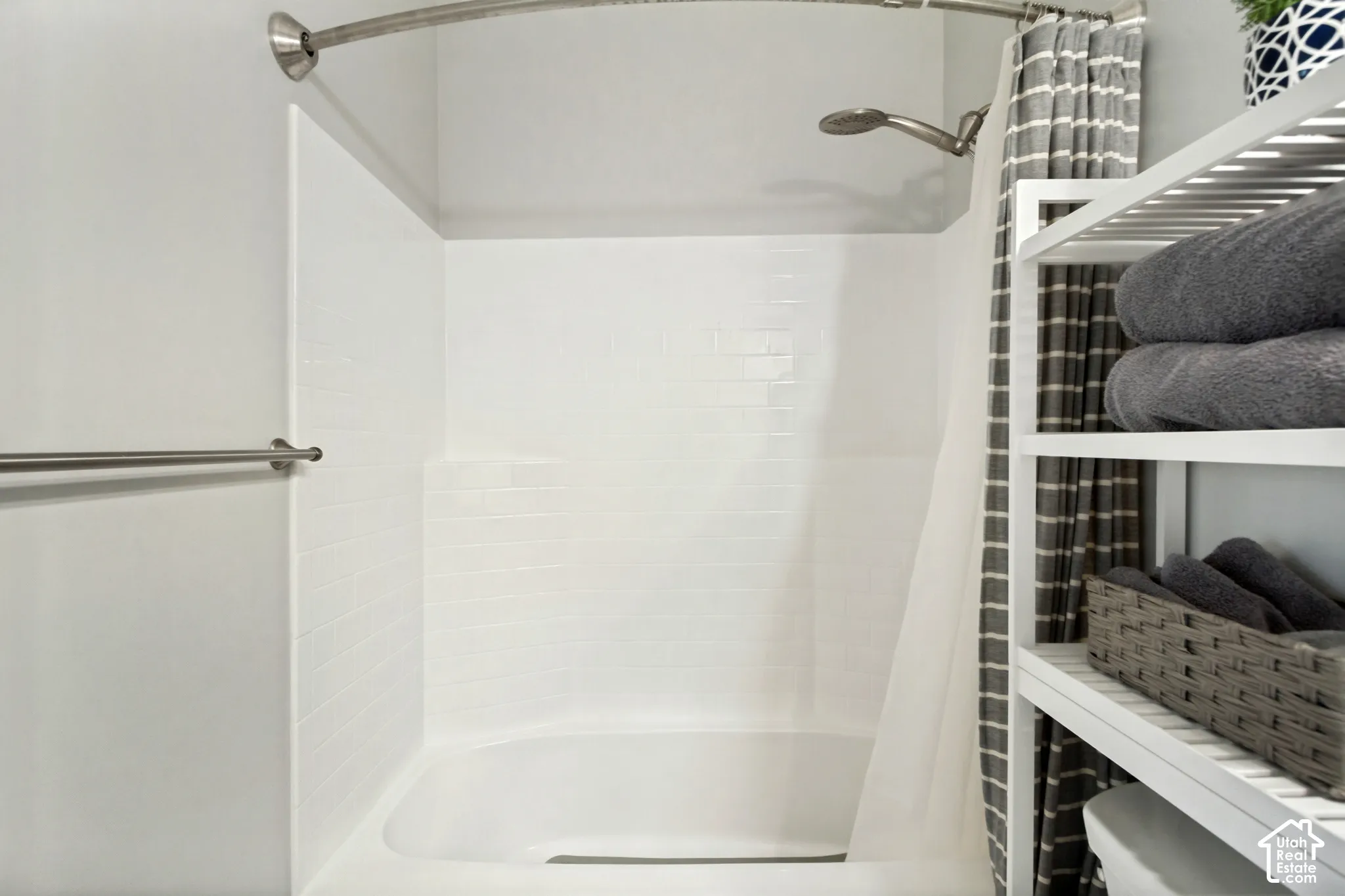Bathtub with an integrated shower, white subway tile-inspired surround, and a curved shower rod