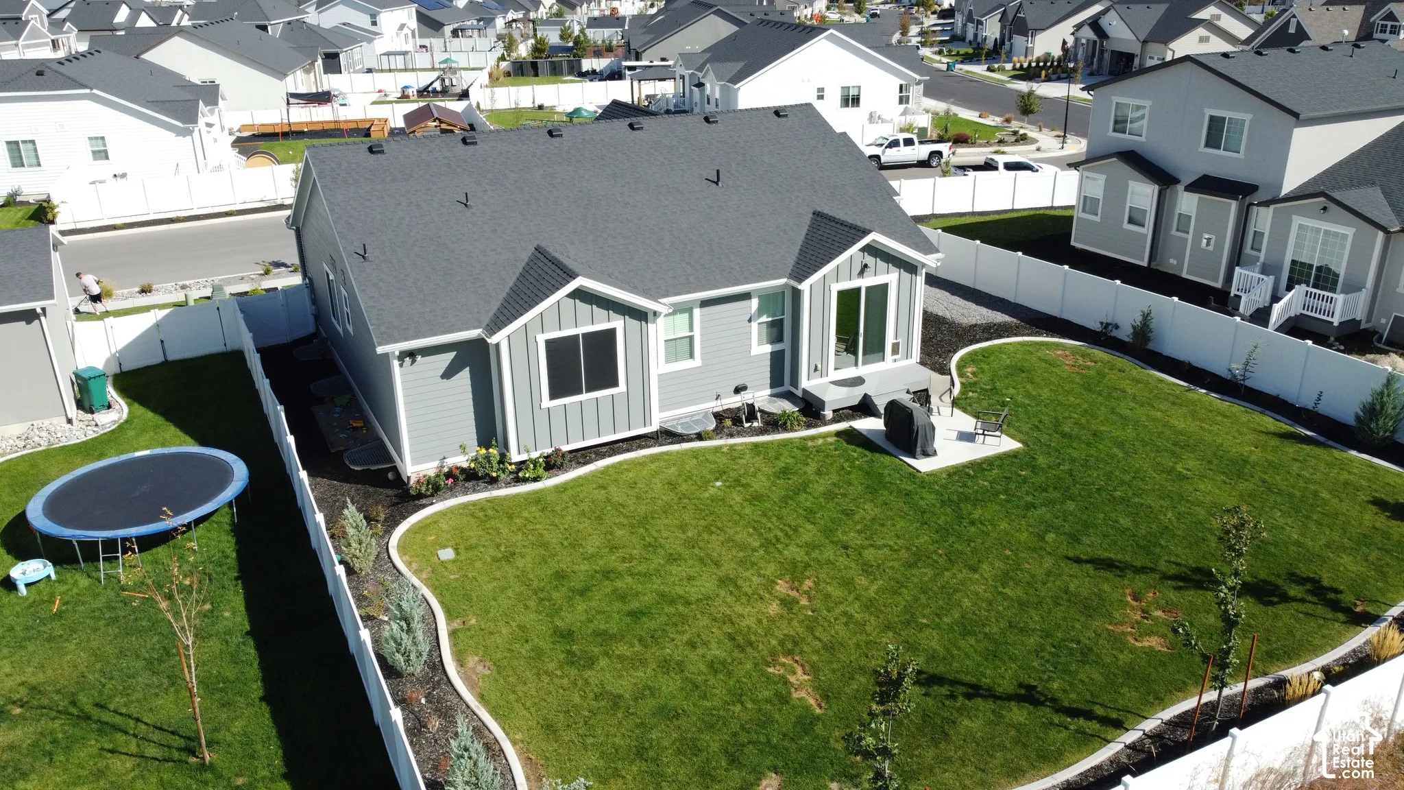 Expansive backyard with manicured lawn, established landscaping, and a concrete patio