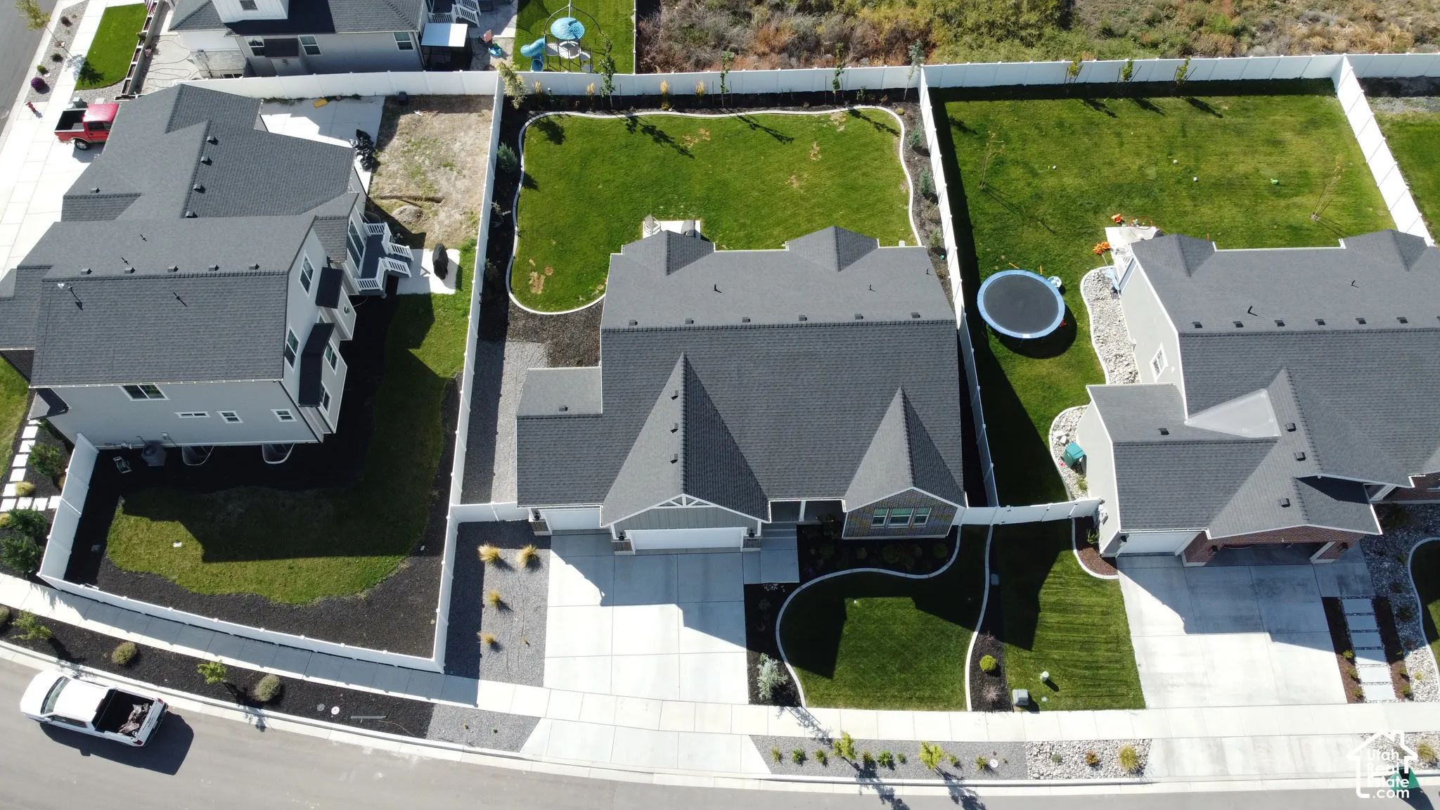 Aerial overview showcasing a property with a paved driveway, a manicured lawn, and perimeter fencing