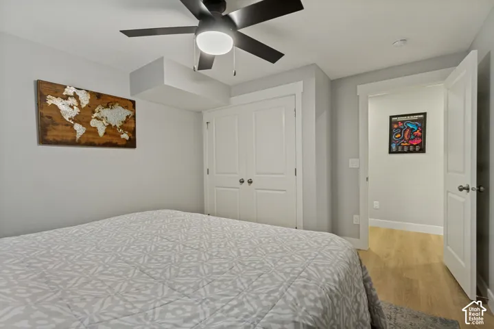 Ceiling fan with integrated lighting, double-door closet, light LVP flooring, and white trim