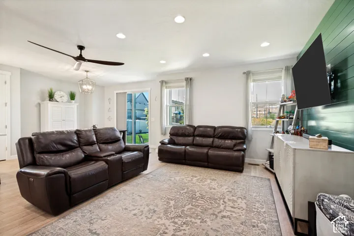 Recessed lighting, LVP flooring, ceiling fan, sliding glass door, and accent wall with horizontal paneling
